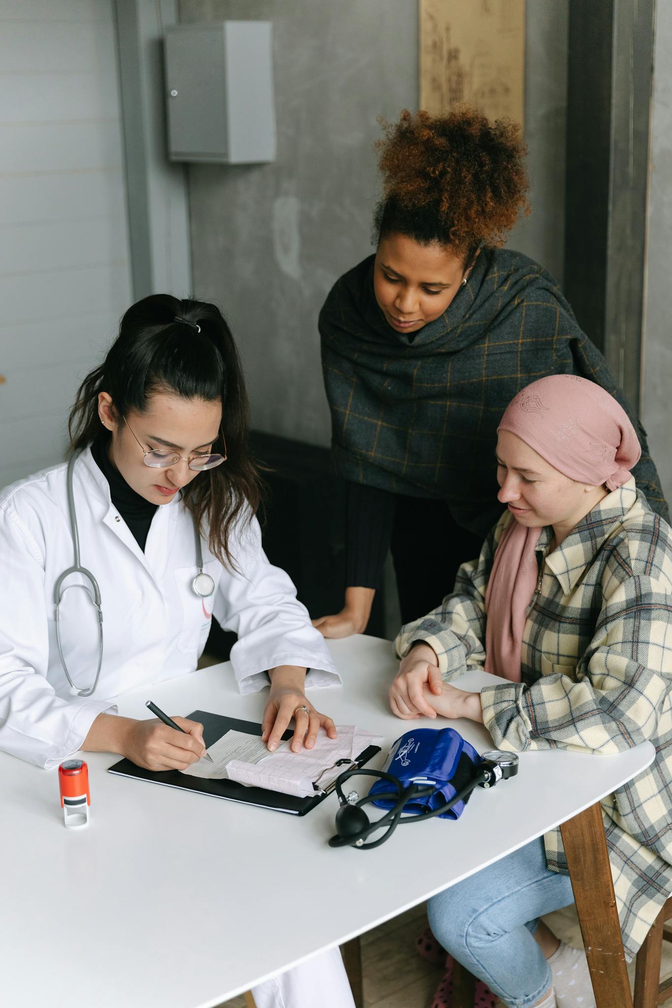A female doctor consults two patients at a desk in a medical clinic, emphasizing diversity and professionalism.